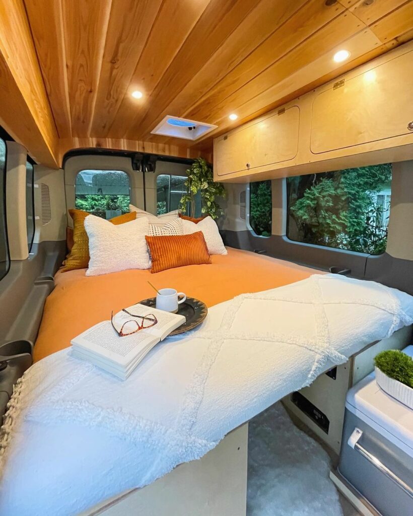 camper van conversion layout around large comfy bed