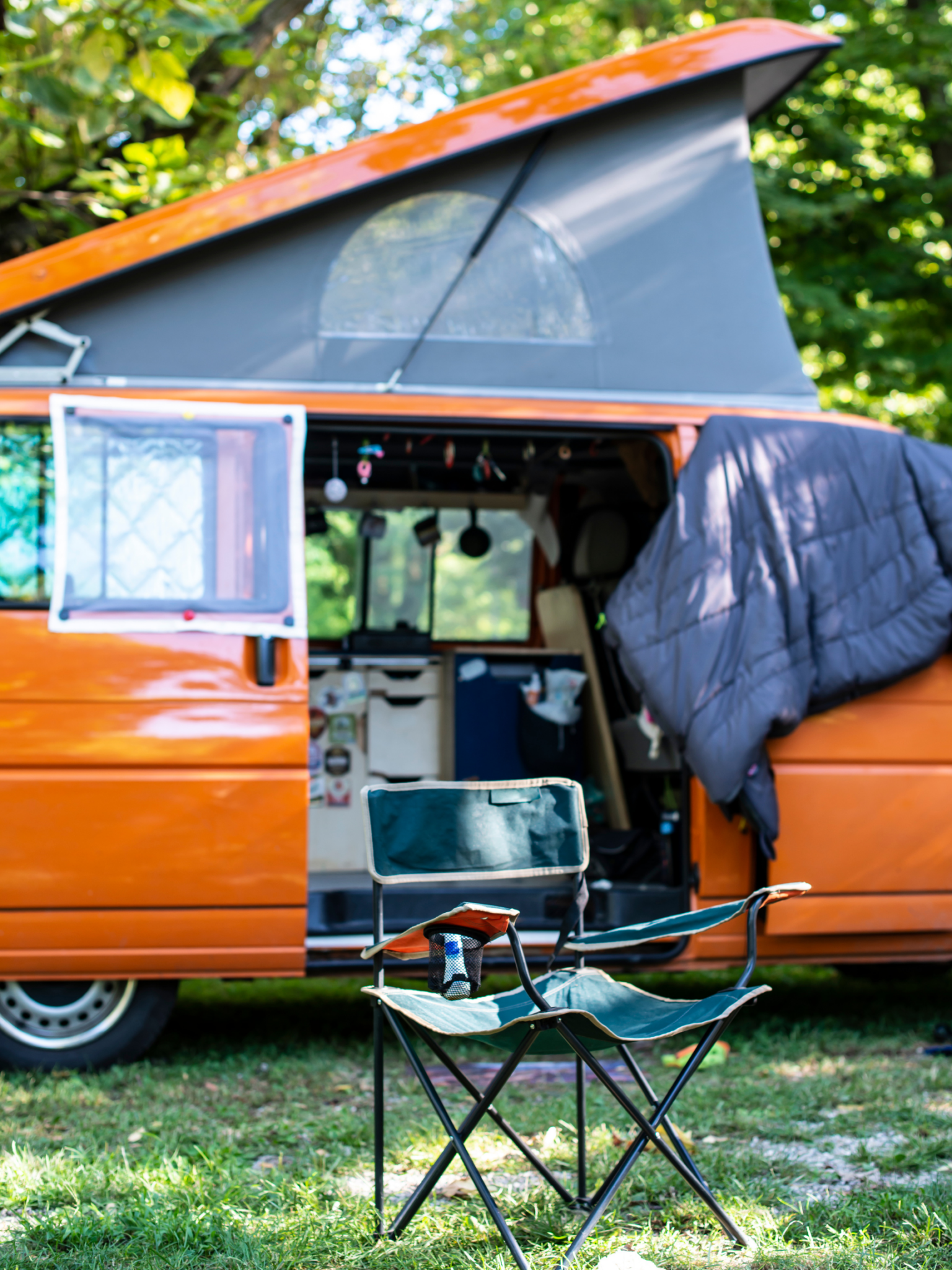 Camping chair in front of orange pop top van