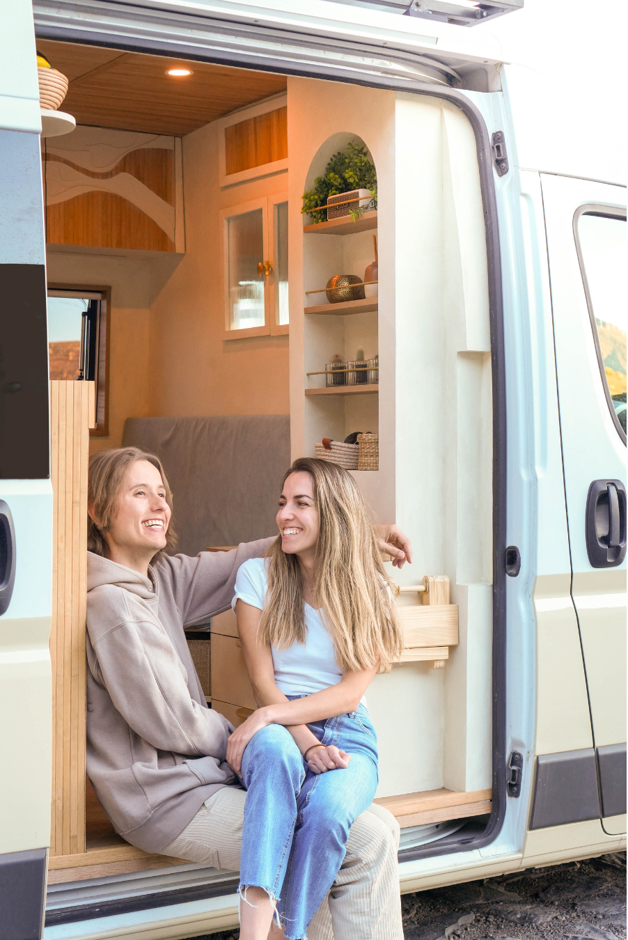 couple sits in door of camper van showing decor