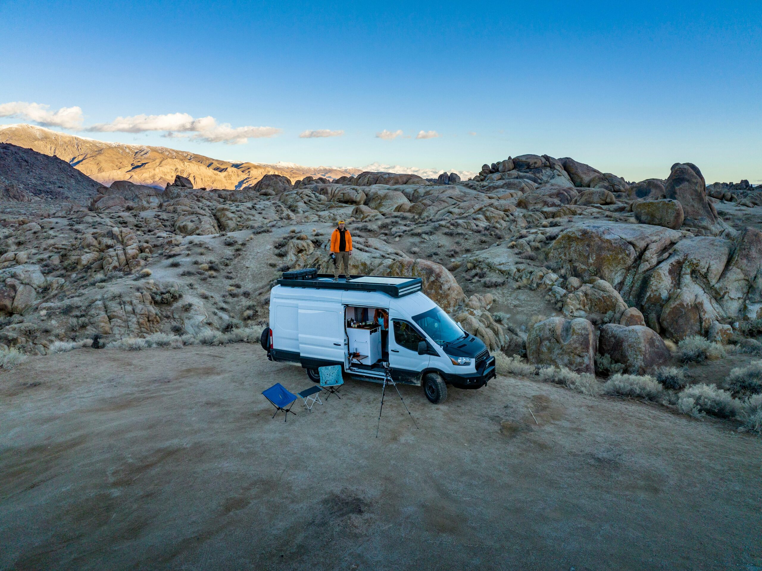 Person standing on top of camper van in rocky terrain