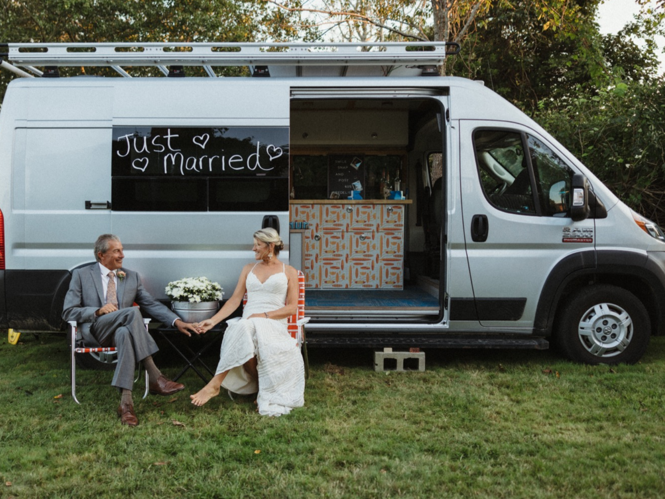 Couple on honeymoon by campervan that says "just married"