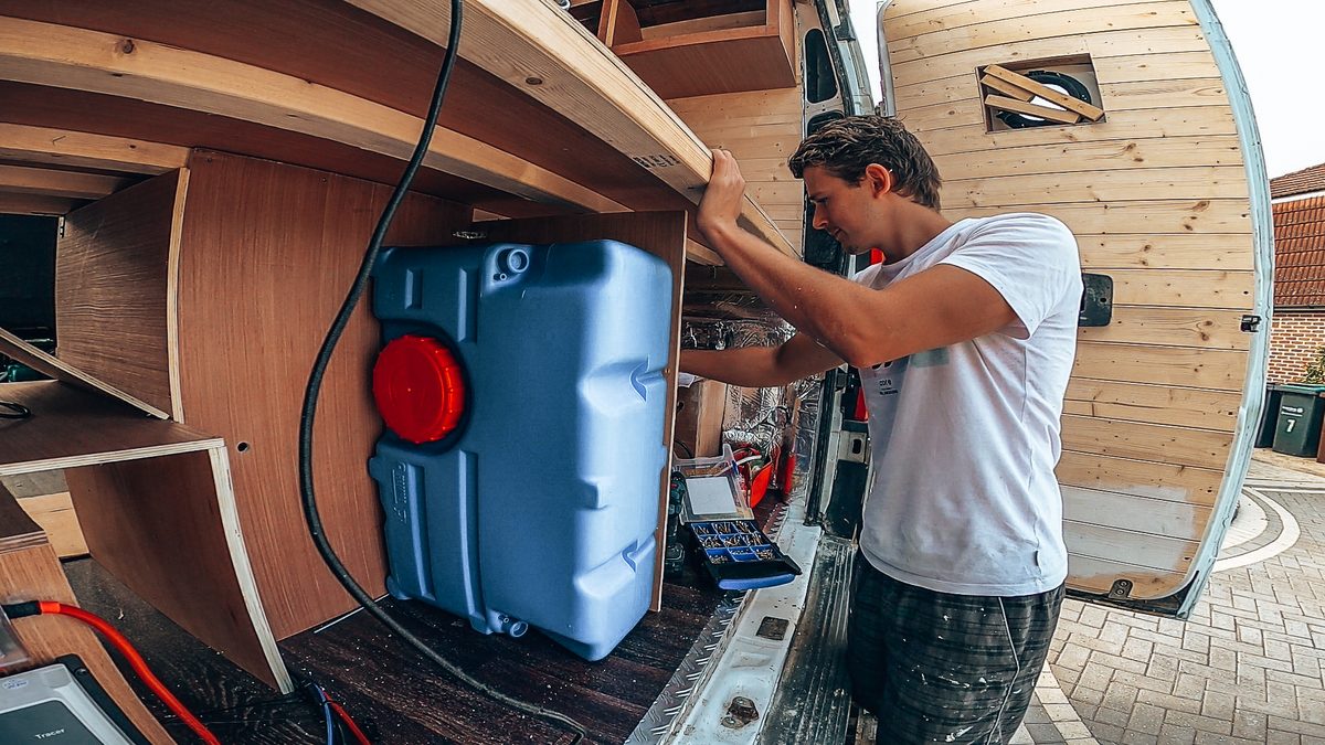 Person installing a shower water tank in a van