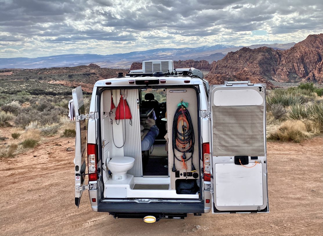 Camper van with back doors open showing a bathroom