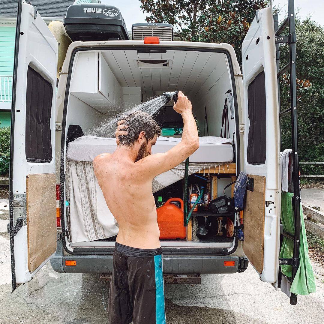 Person using a shower out the back of a camper van