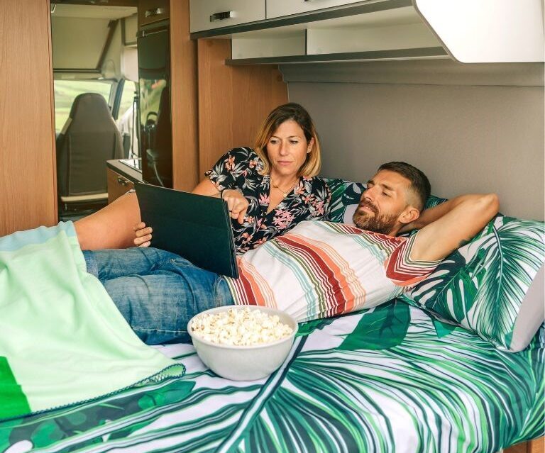 Couple watching movie in campervan bed