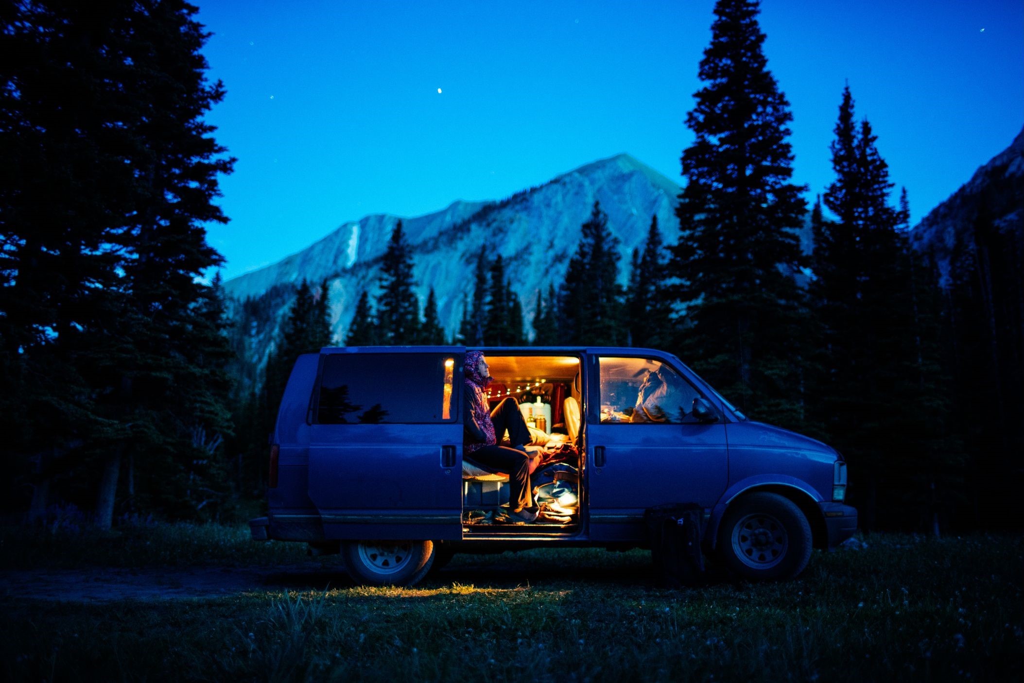 Person camping in a van near mountains